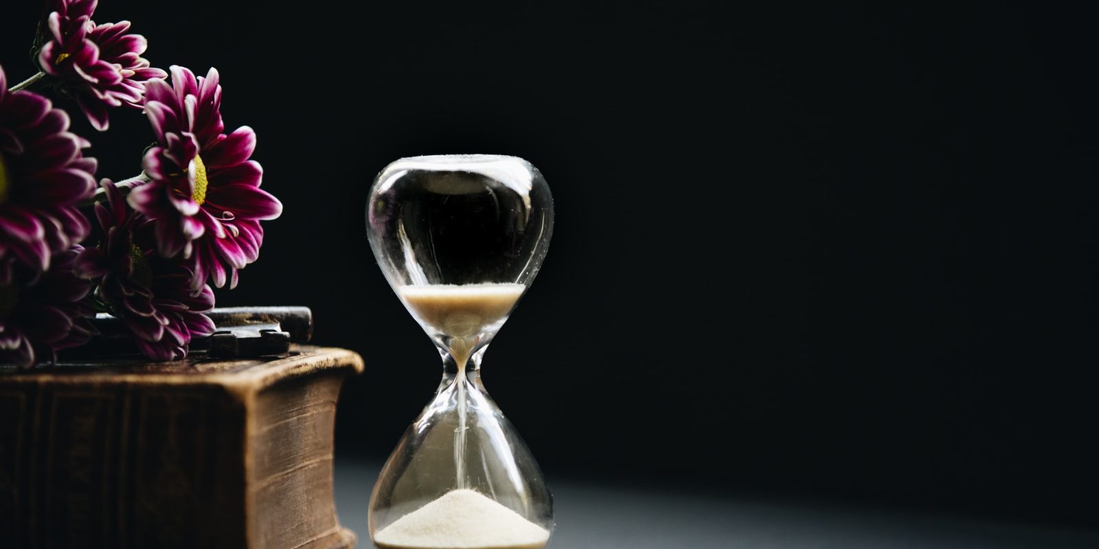 clear hour glass beside pink flowers