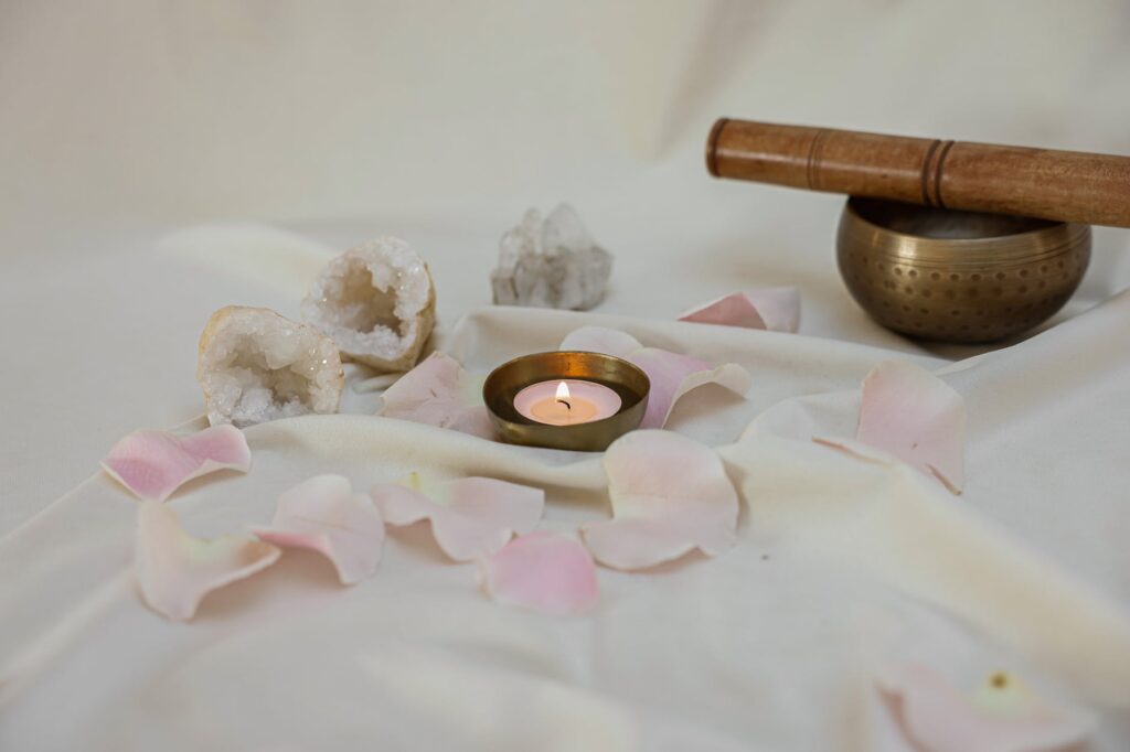 lighted candle beside a tibetan singing bowl on white linen