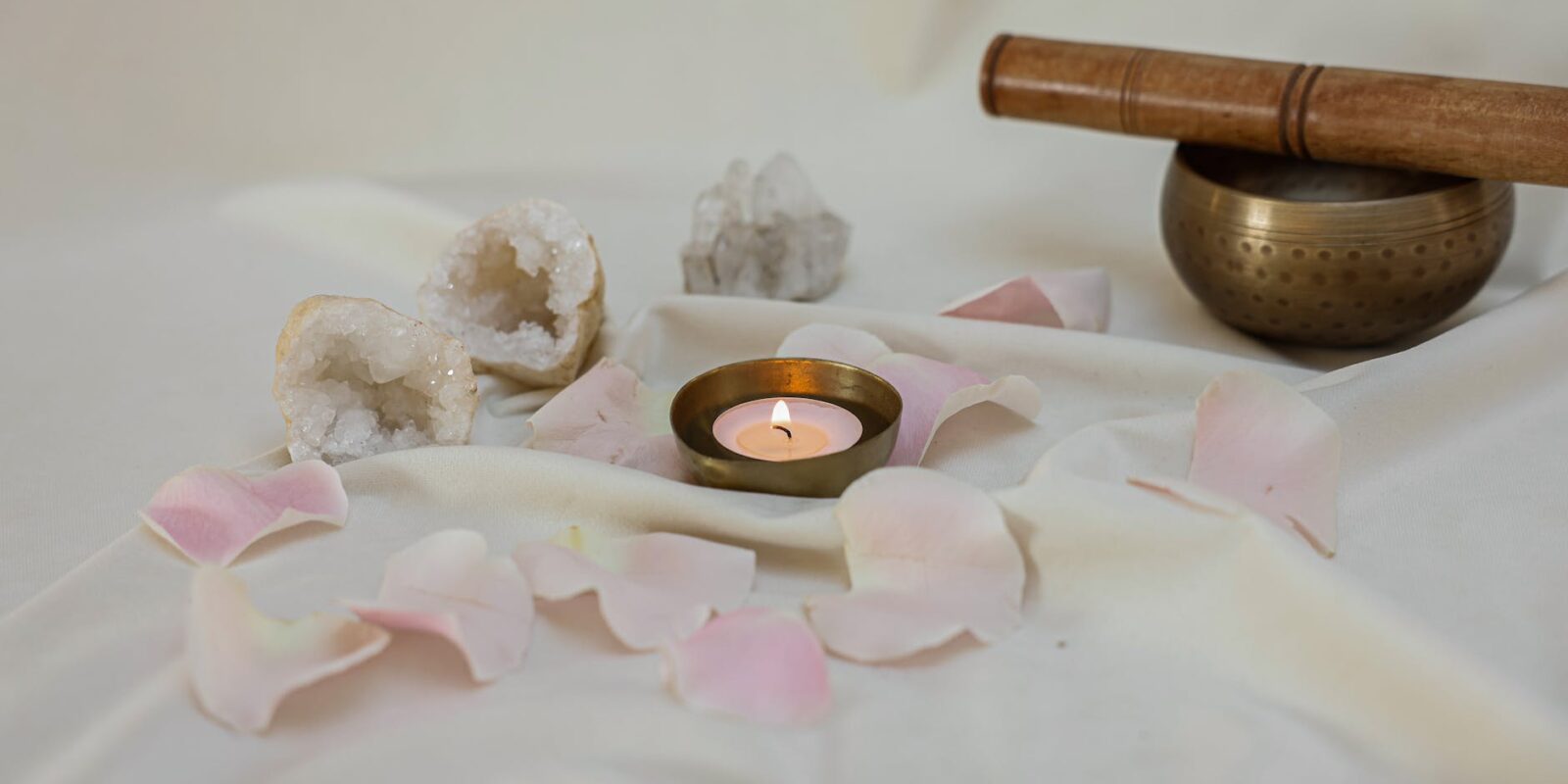 lighted candle beside a tibetan singing bowl on white linen